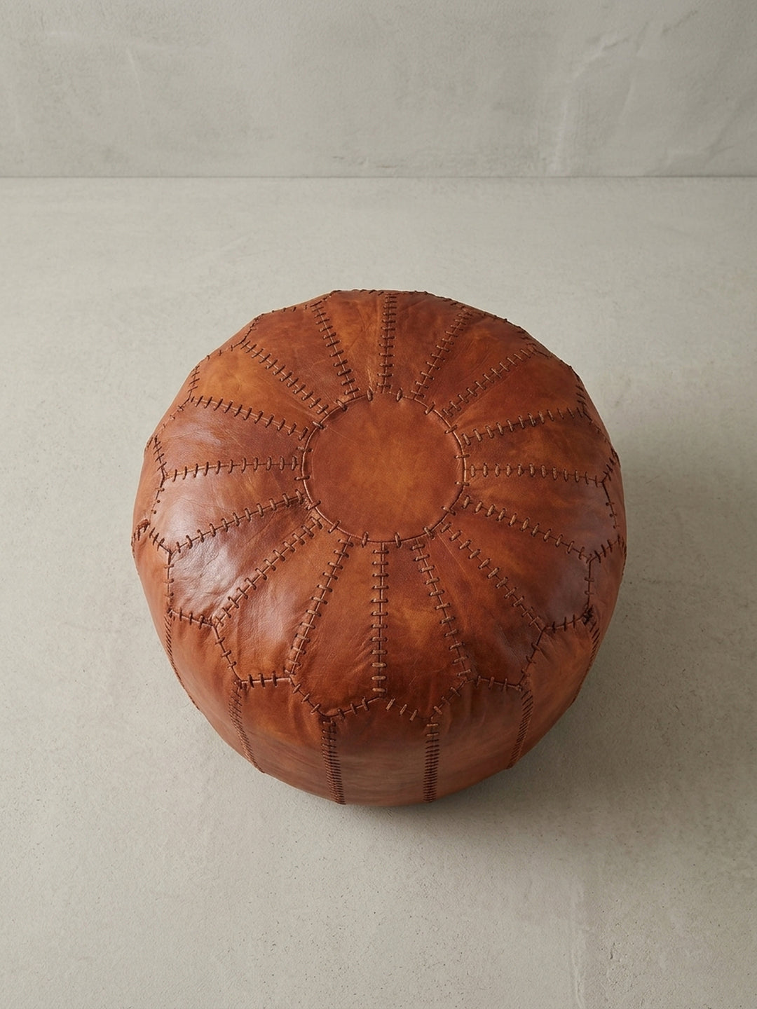 Schräge Draufsicht auf den braunen Leder Pouf, der seine großzügige Sitzfläche und das voluminöse Design elegant hervorhebt._