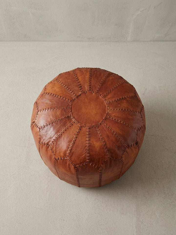 Schräge Draufsicht auf den braunen Leder Pouf, der seine großzügige Sitzfläche und das voluminöse Design elegant hervorhebt._