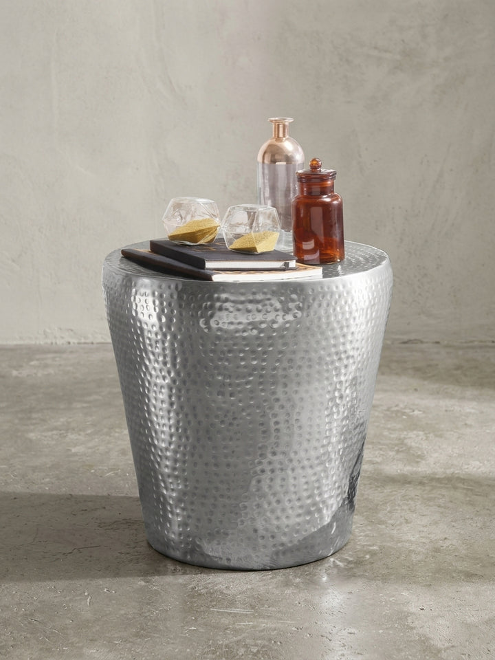 Zylindrischer Beistelltisch aus Aluminium in glänzendem Silber vor weißem Hintergrund. Der 41cm hohe, runde Dekotisch zeigt sein charakteristisches, orientalisches Hammerschlag-Design._