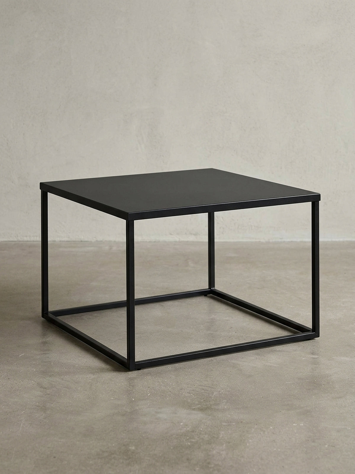 Frontansicht des quadratischen Couchtischs aus schwarzem Stahl, der seine minimalistische, kubische Silhouette auf weißem Hintergrund zeigt.