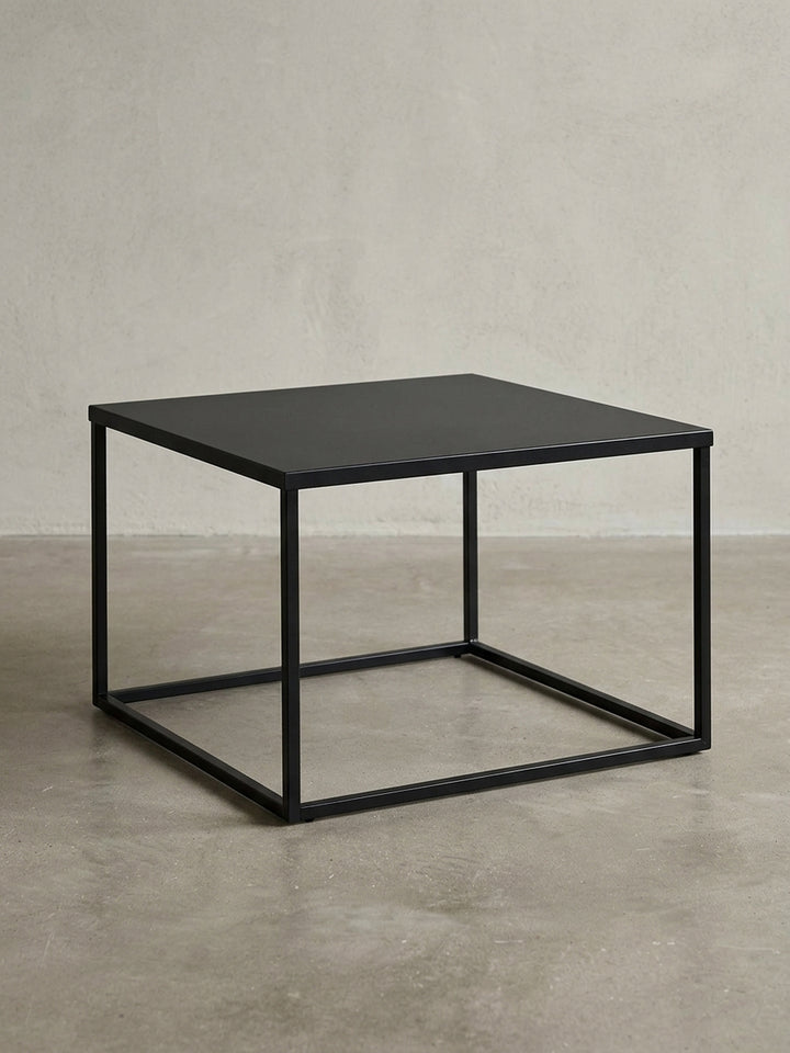 Frontansicht des quadratischen Couchtischs aus schwarzem Stahl, der seine minimalistische, kubische Silhouette auf weißem Hintergrund zeigt._