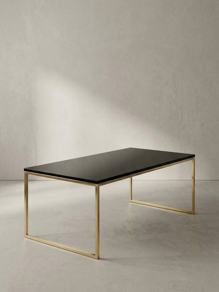 Rechteckiger Couchtisch aus schwarz lackiertem MDF und goldfarben lackiertem Stahl in der Frontalansicht vor neutralem Hintergrund._