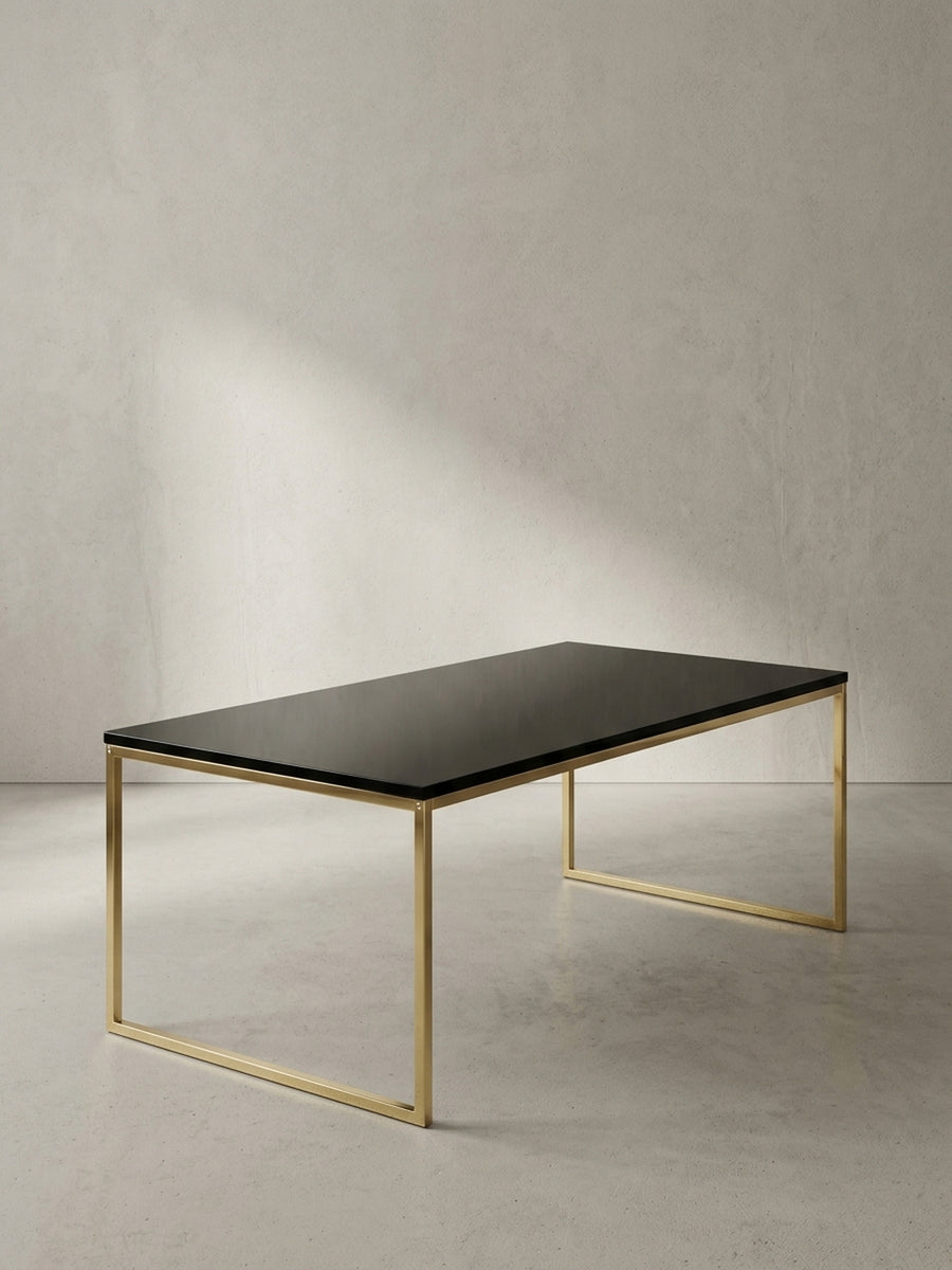 Rechteckiger Couchtisch aus schwarz lackiertem MDF und goldfarben lackiertem Stahl in der Frontalansicht vor neutralem Hintergrund._
