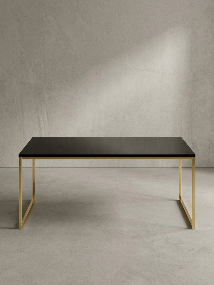 Schräger Blick auf den Design Wohnzimmertisch in Schwarz und Gold, der die schlanke Silhouette und das offene Rahmendesign aus lackiertem Metall zeigt._