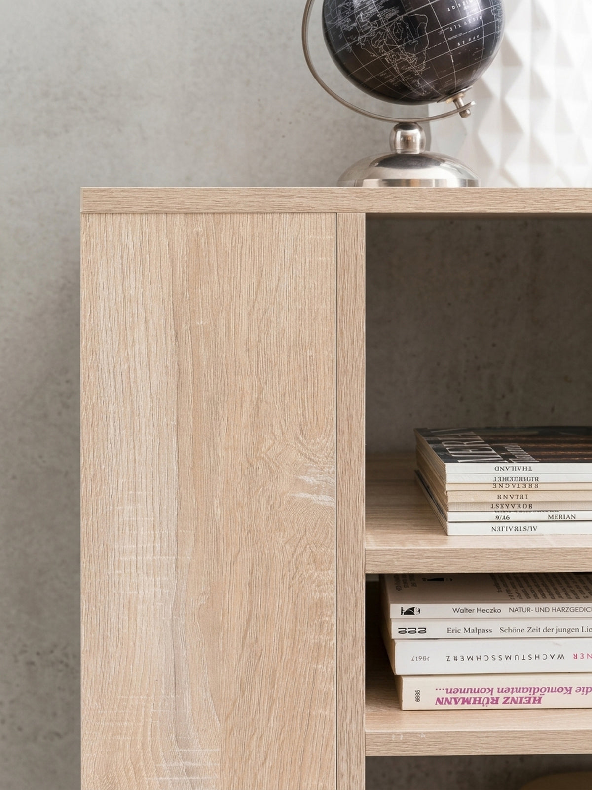 Nahaufnahme der schwarzen Kunststoffrollen am Standcontainer. Sie garantieren Flexibilität und 5cm Bodenfreiheit für das kleine Bücherregal in natürlicher heller Eichenholz-Optik._