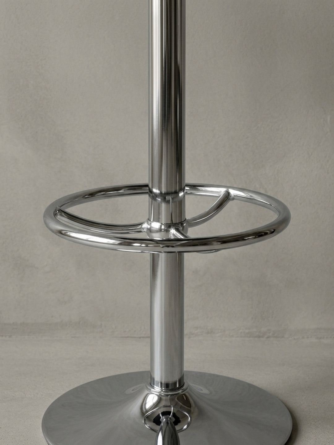 Alternative Perspektive auf den runden Bistrotisch. Die Spiegelungen im polierten Aluminiumgestell betonen die hochwertige Verarbeitung der ringförmigen Fußstütze und der Chromkante._