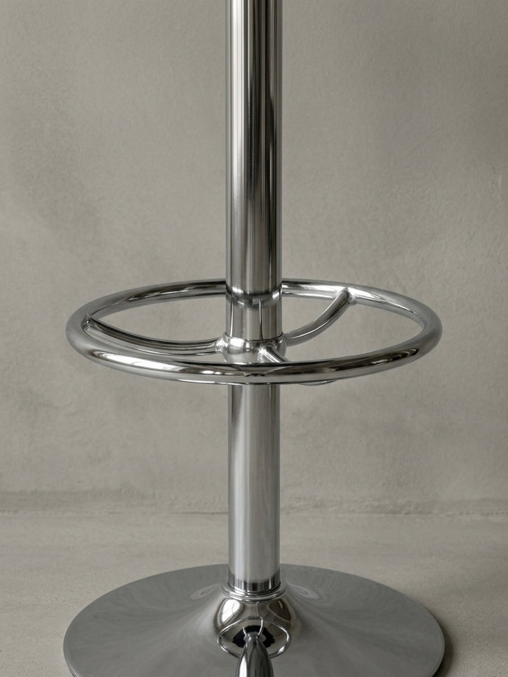 Alternative Perspektive auf den runden Bistrotisch. Die Spiegelungen im polierten Aluminiumgestell betonen die hochwertige Verarbeitung der ringförmigen Fußstütze und der Chromkante._