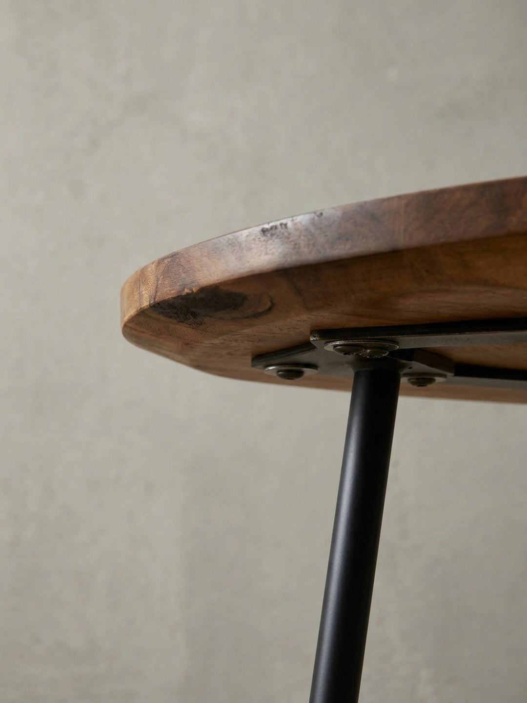 Detailfoto der schwarzen, pulverbeschichteten Tischbeine am Massivholztisch. Der Übergang vom Metallgestell zur klarlackierten Holztischplatte zeigt die solide Verarbeitung._