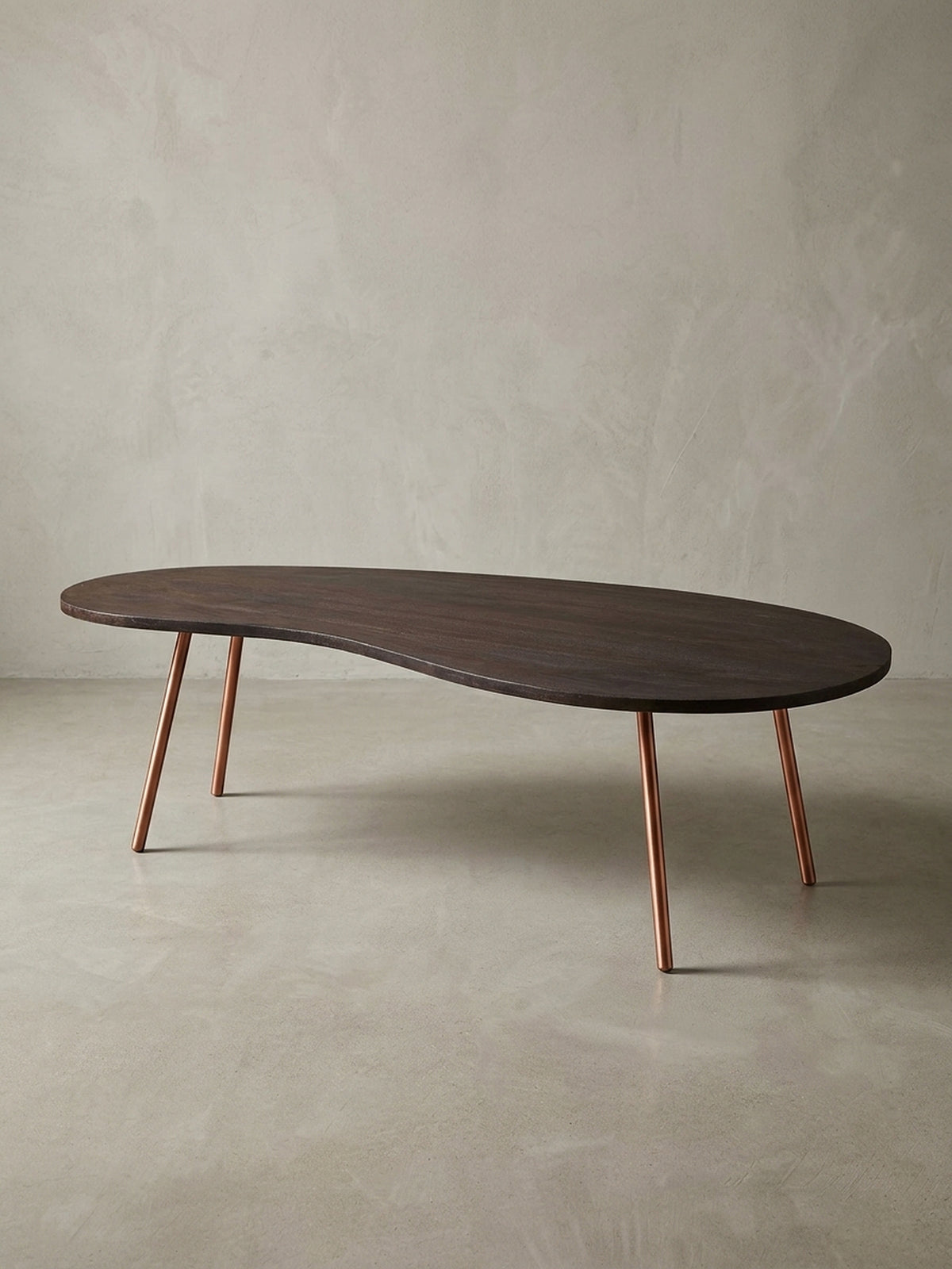 Freigestellter Design Couchtisch Nierentisch in Dunkelbraun mit schräg gestellten kupferfarbenen Metallbeinen. Mid-Century Stil für moderne Wohnzimmer und stilvolle Einrichtungen._
