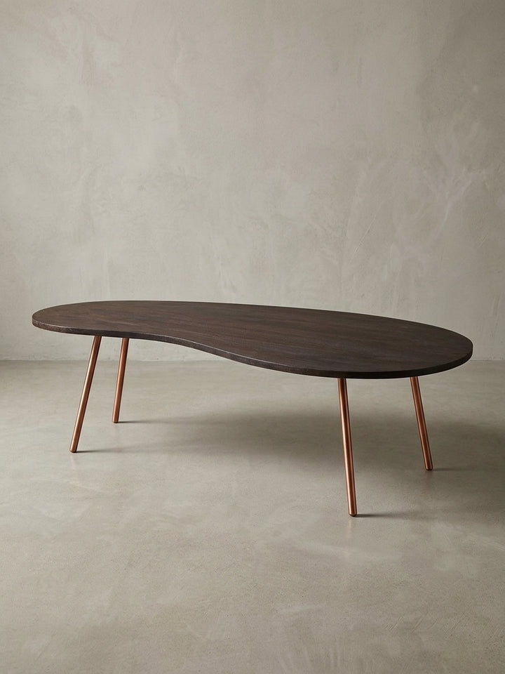 Freigestellter Design Couchtisch Nierentisch in Dunkelbraun mit schräg gestellten kupferfarbenen Metallbeinen. Mid-Century Stil für moderne Wohnzimmer und stilvolle Einrichtungen._