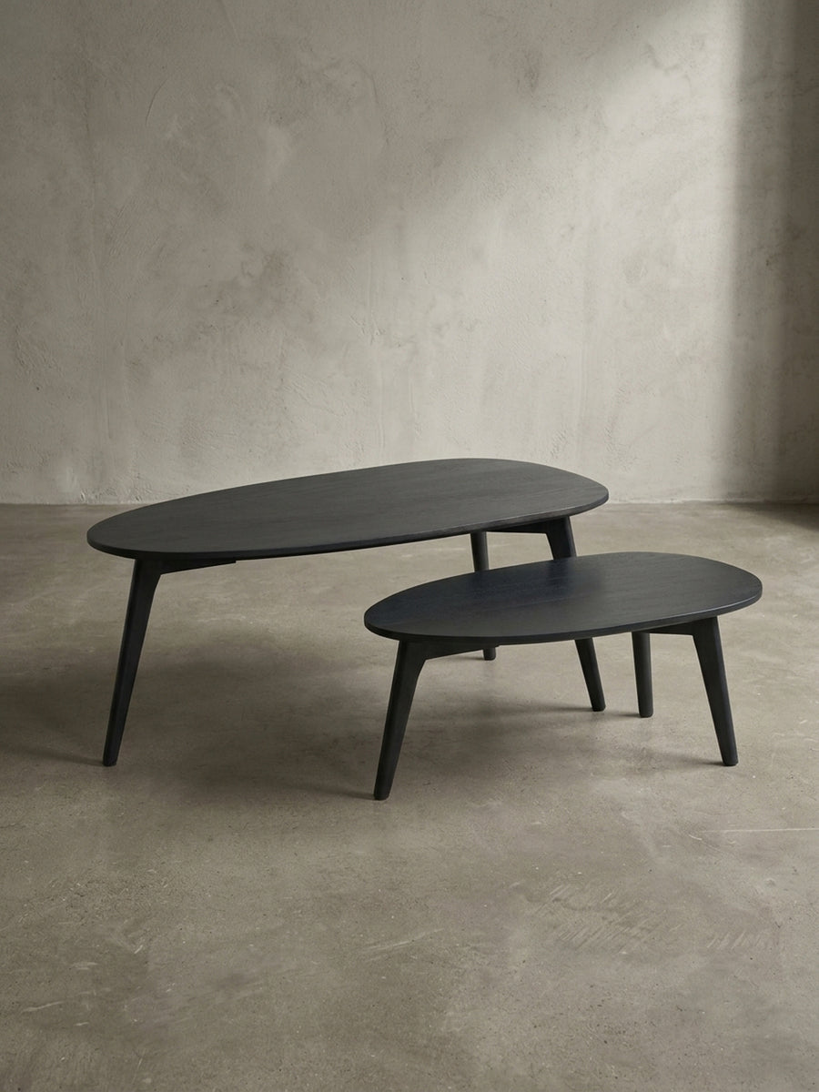 Blick auf das flexible Arrangement der beiden schwarzen Satztische aus Massivholz, der kleinere Tisch platzsparend unter den größeren geschoben._