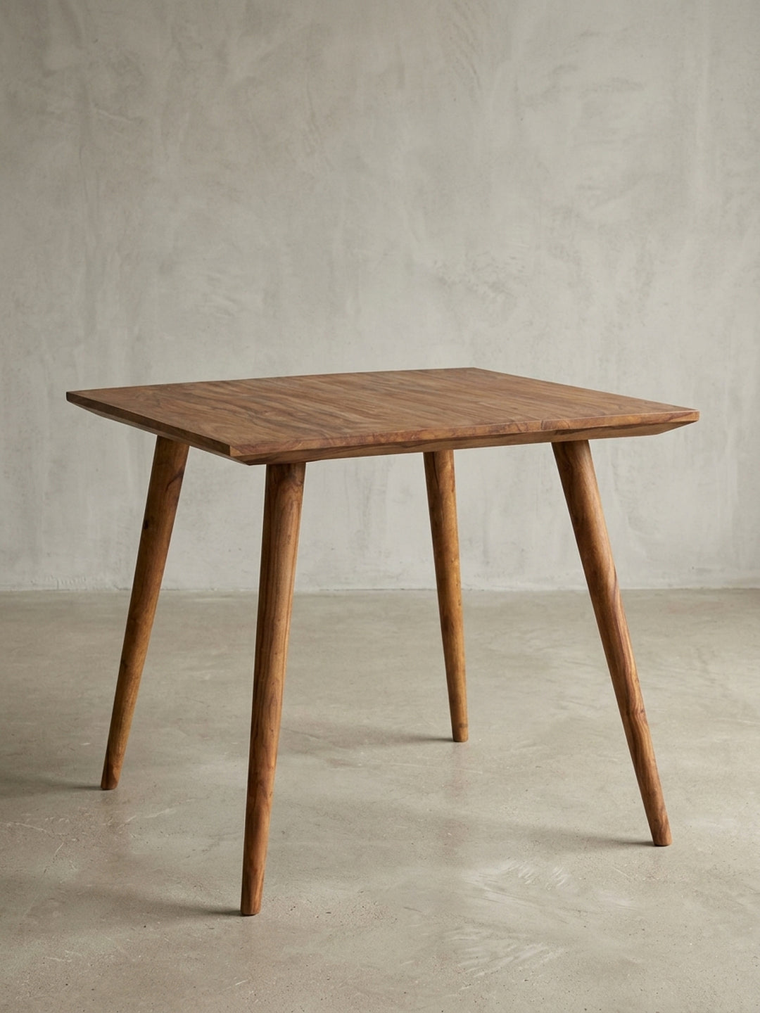 Esstisch aus warmem Sheesham-Massivholz mit markanter Maserung auf neutralem Betonhintergrund Frontalansicht 80x80x76 cm_