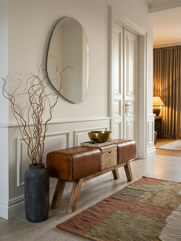 Draufsicht auf die Flurbank aus Ziegenleder und Mangoholz. Die 120cm lange Garderobenbank fügt sich mit ihrem praktischen Klappfach perfekt in die räumliche Flur-Komposition ein._