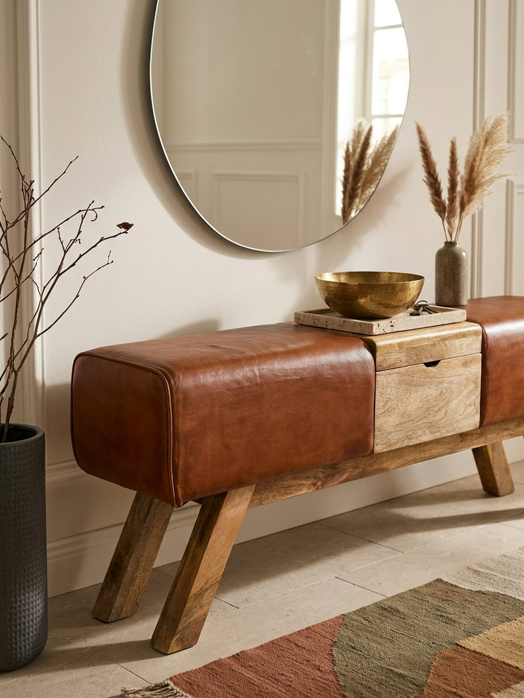 Nahaufnahme der Sitzbank: Feine Narbung des braunen Ziegenleders trifft auf die warme, lebhafte Maserung des massiven Mangoholzes. Hochwertige Verarbeitung für den Eingangsbereich._