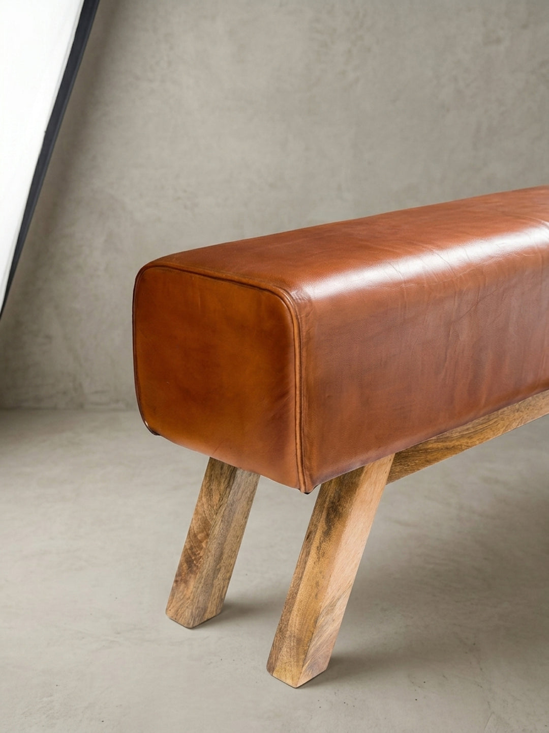 Alternative Ansicht der Turnbock Bank, die das zentrale Aufbewahrungsfach fokussiert. Das braune Leder und das helle Mangoholz bilden einen warmen Kontrast für moderne Flure._