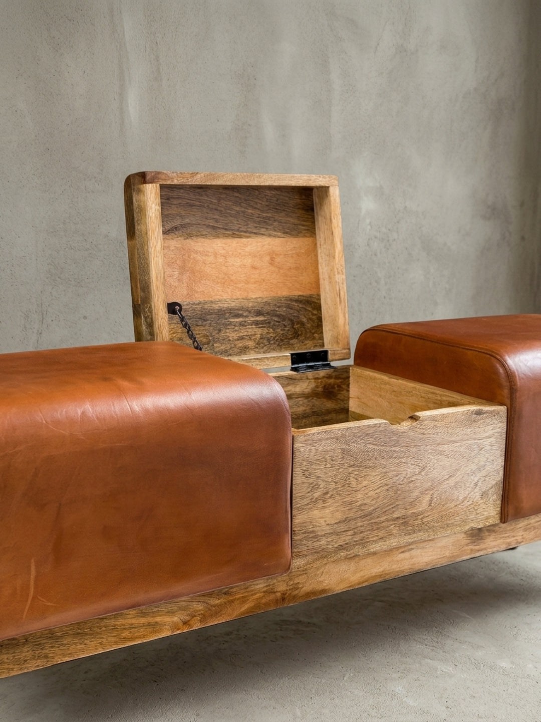 Detailaufnahme des integrierten Klappfachs der Holzbank. Das praktische Staufach im massiven Mangoholz-Mittelteil bietet unauffälligen Platz, umrahmt von feinem Echtleder._