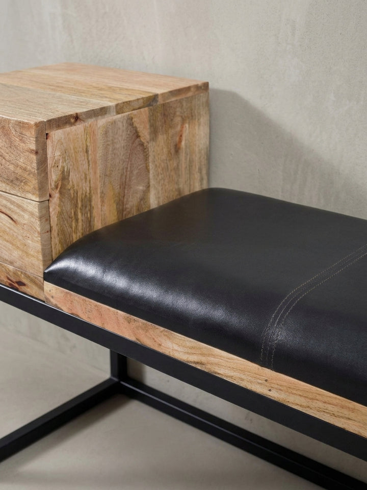 Asymmetrisches Design der Sitzbank mit Stauraum, bei der das Holzelement mit Schubladen einen spannenden Kontrast zur gepolsterten Lederfläche bildet._