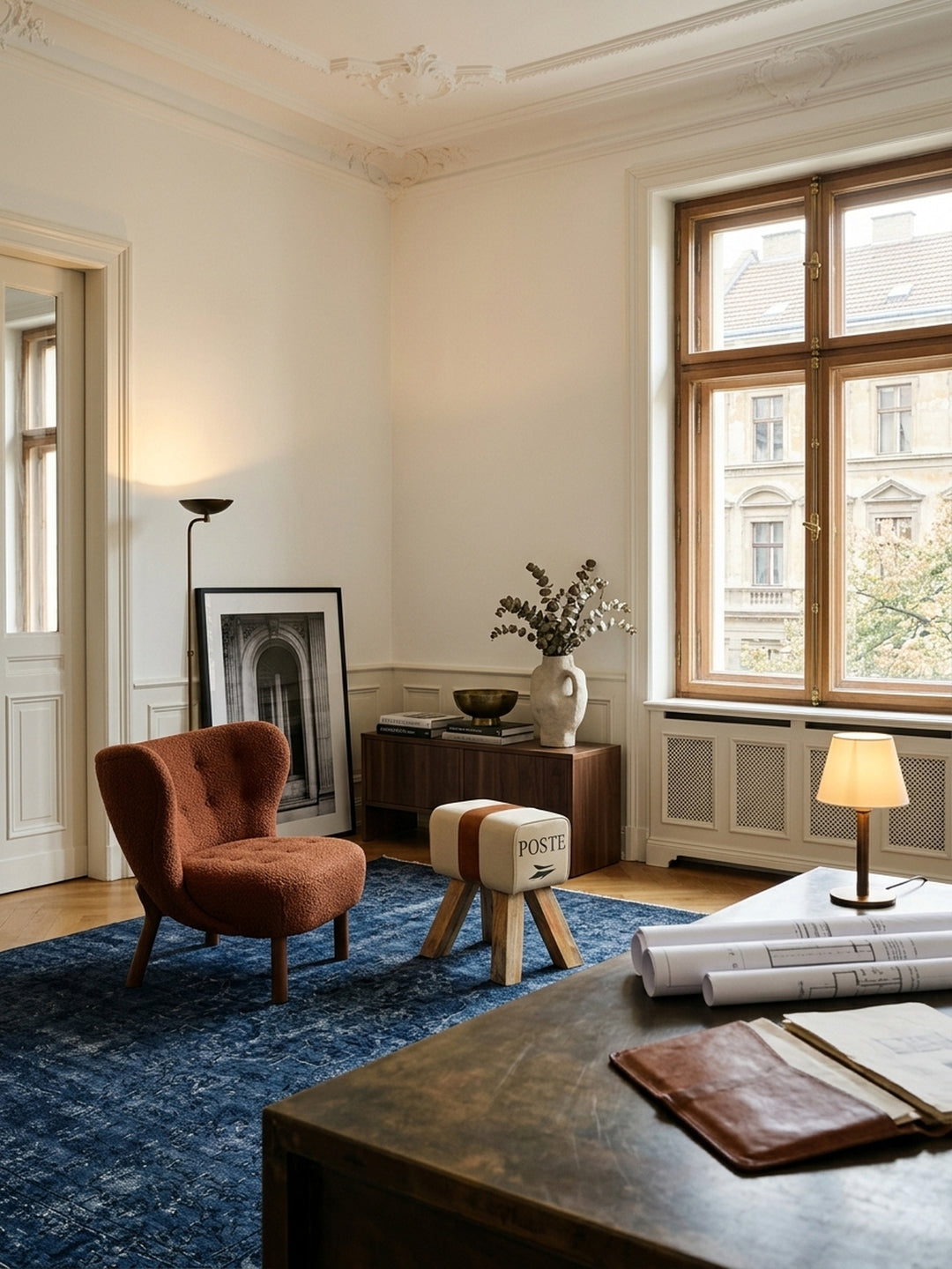 Eleganter Vintage Turnhocker im gehobenen Arbeitszimmer. Der kleine Sitzhocker aus beigem Canvas und braunem Echtleder steht stilvoll auf dunklem Parkett neben einer edlen Holzkonsole._