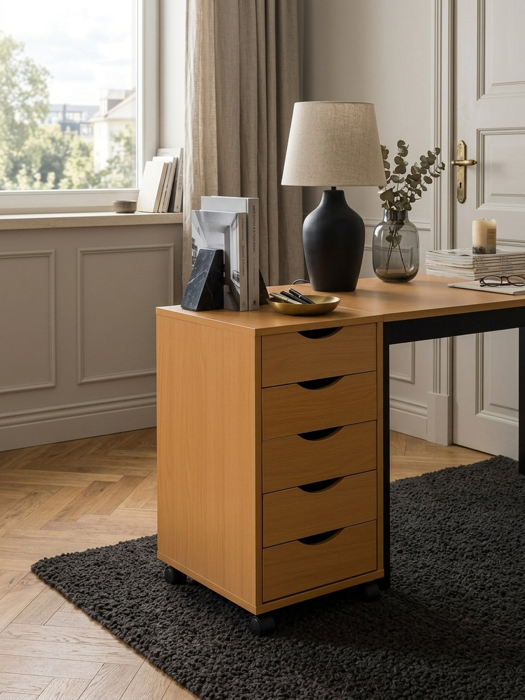 Draufsicht auf den kompakten Schreibtisch-Container im Arbeitszimmer. Der holzfarbene Rollschrank zeigt seine 33x38cm Ablagefläche neben einem dunklen Wollteppich._