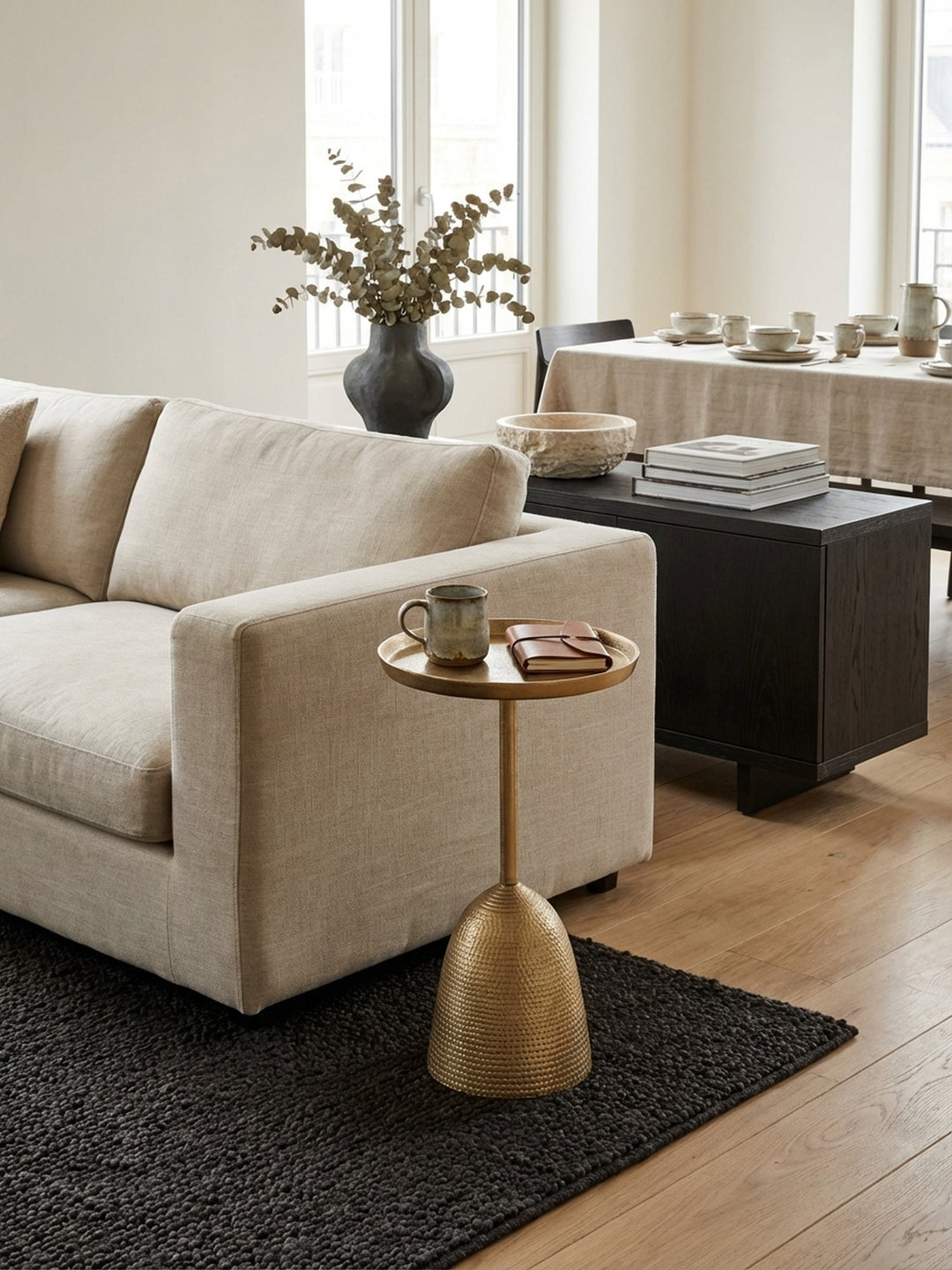 Eleganter goldener Beistelltisch aus Aluminium neben einem Sofa in einem modernen Wohnzimmer, perfekt als stilvolle Ablage für Getränke und Bücher._