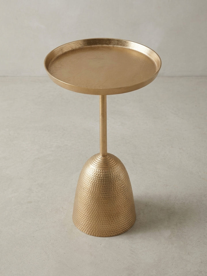 Skulpturaler Wohnzimmertisch in Gold, aus einer alternativen Perspektive, die das Zusammenspiel von glatter Tischplatte und texturiertem Fuß betont._