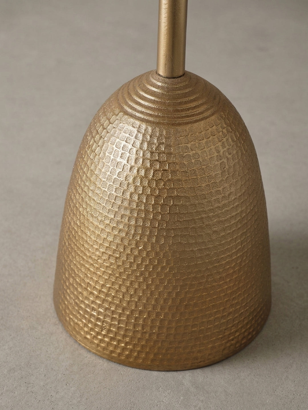 Detailaufnahme des Übergangs vom schlanken Bein zum gehämmerten Fuß des goldenen Beistelltisches, der die hochwertige Verarbeitung des Aluminiums zeigt._