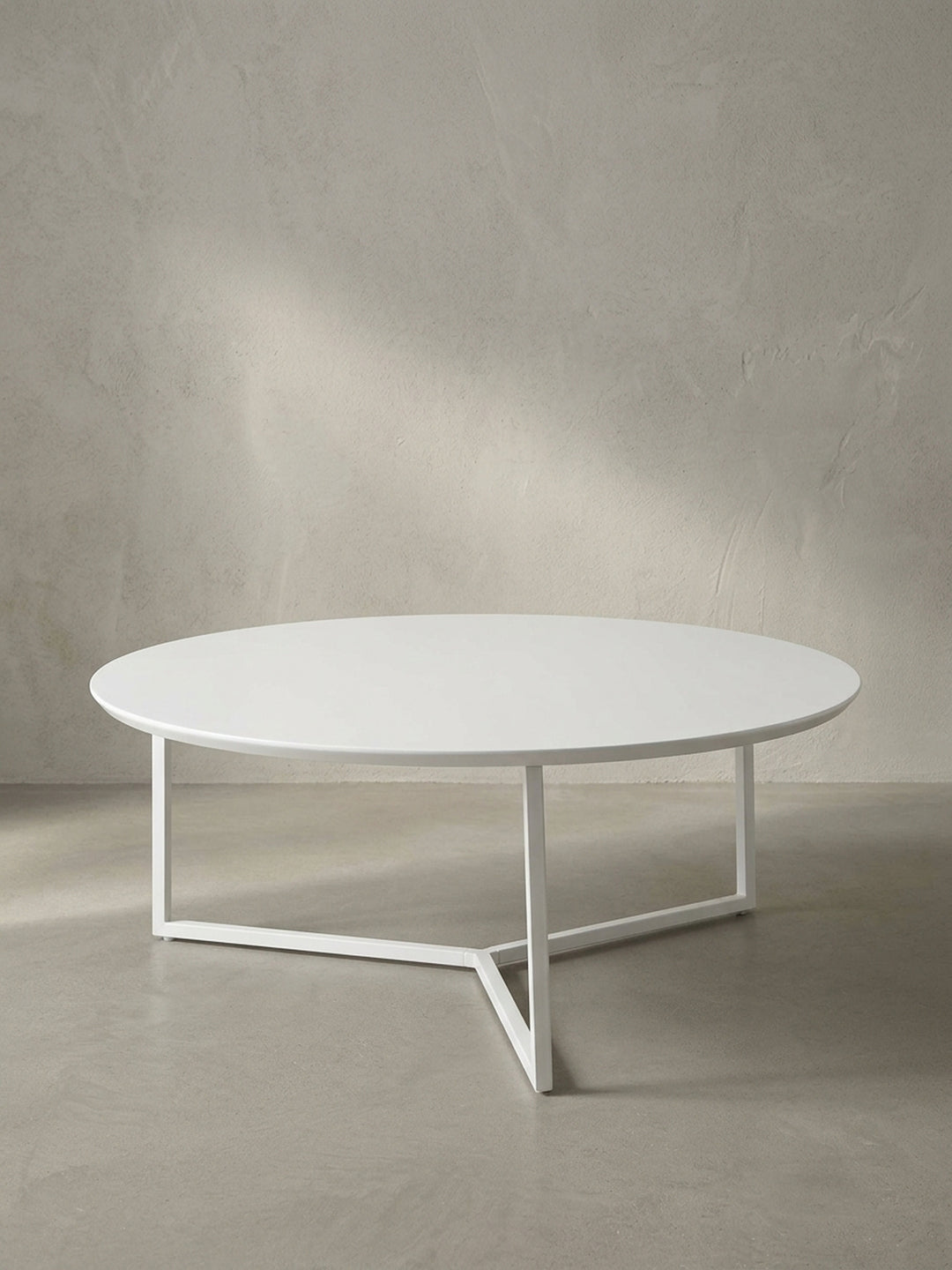 Vollansicht des runden Design-Couchtisches mit 80 cm Durchmesser aus weiß lackierter MDF-Platte und filigranem dreibeinigen Metallrahmen vor neutralem Hintergrund._