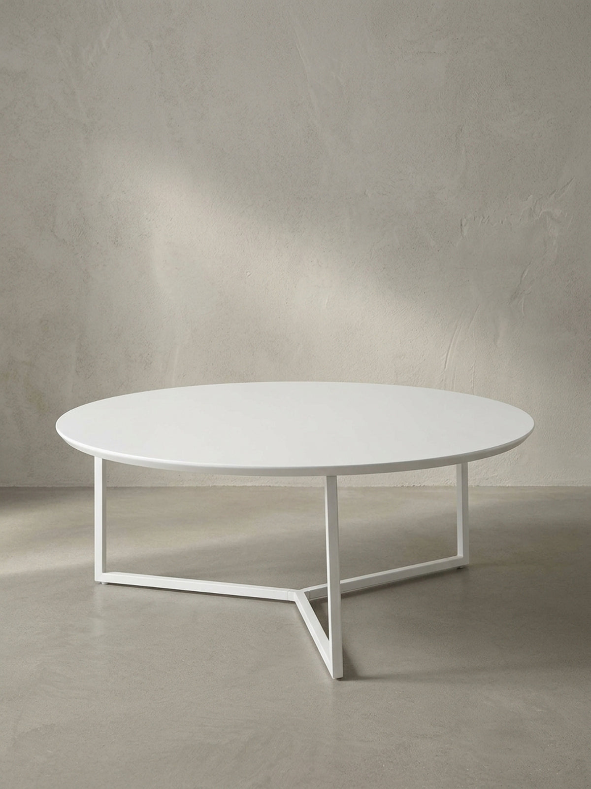 Vollansicht des runden Design-Couchtisches mit 80 cm Durchmesser aus weiß lackierter MDF-Platte und filigranem dreibeinigen Metallrahmen vor neutralem Hintergrund.