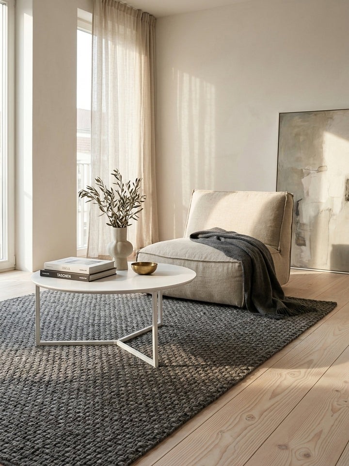 Minimalistischer Loungetisch mit weißem Metallgestell kombiniert mit einem sandfarbenen Bouclé-Sofa und einer eleganten Messing-Bogenleuchte im hellen Raum._