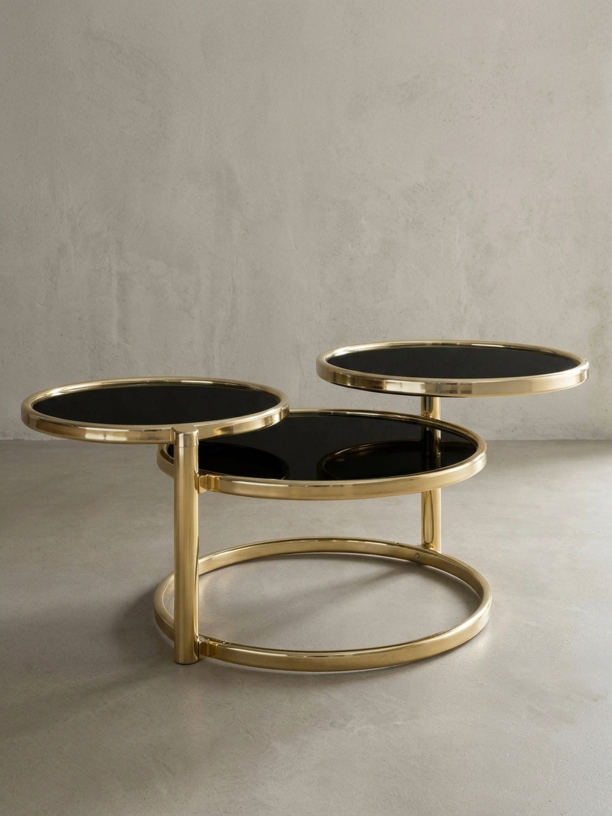 Designer Couchtisch 3 Ebenen in Schwarz und Gold auf weißem Hintergrund. Die kreisrunden Glasplatten und das Metallgestell bilden ein elegantes, klassisch-modernes Design._