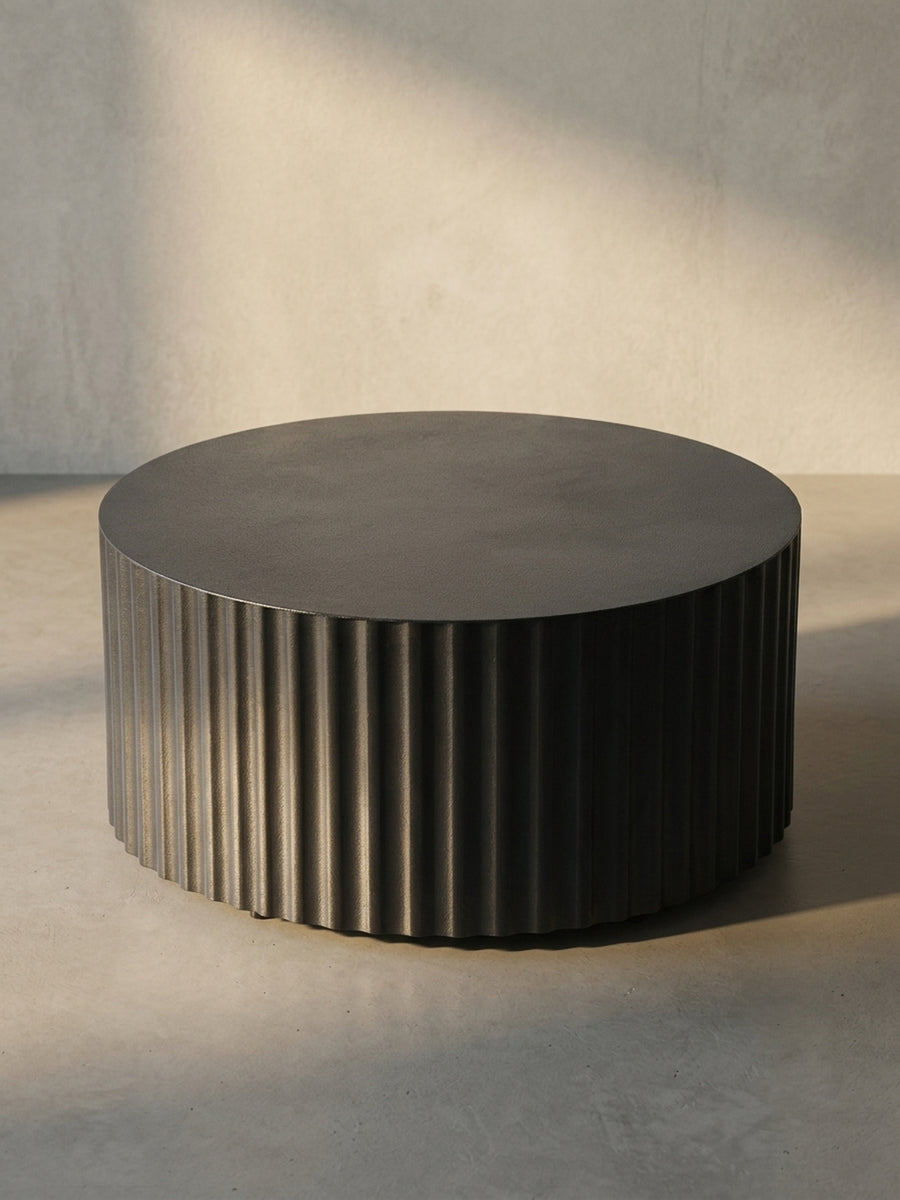 Nahaufnahme der Kante des schwarzen Metall-Couchtischs, die den sauberen Übergang von der glatten Platte zur texturierten Seite zeigt._