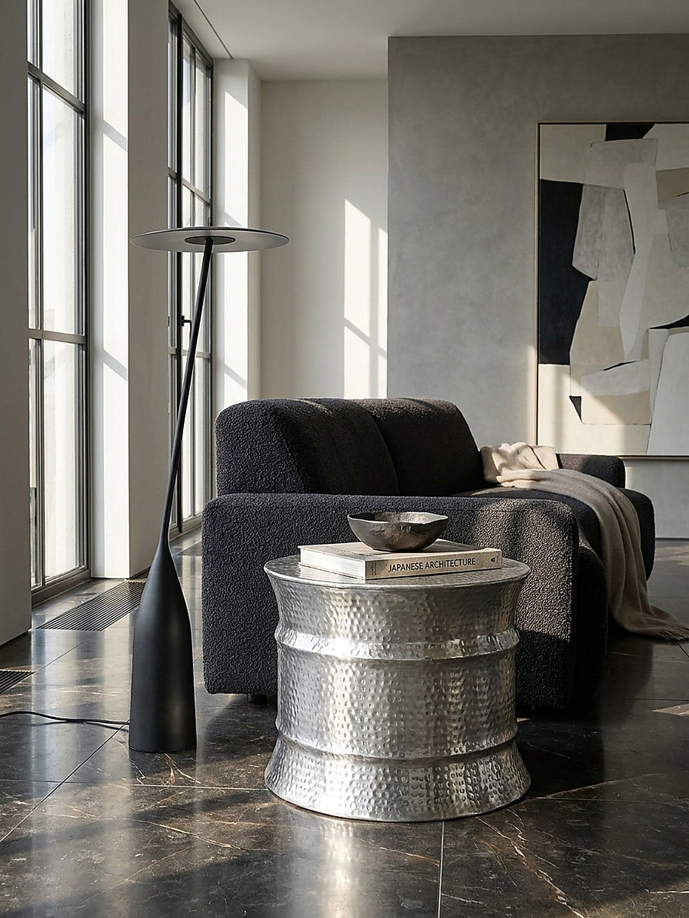 Runder Aluminium-Couchtisch kombiniert mit einem monochromen Sofa in einer kühlen und modernen Architektur-Umgebung_