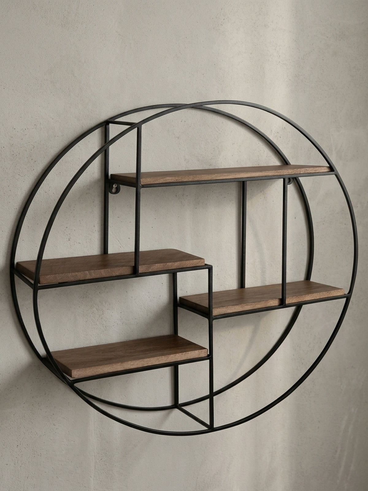 Frontansicht des runden Wandregals mit 70 cm Durchmesser, das die asymmetrische Anordnung der vier Ablagen aus Mangoholz im schwarzen Metallrahmen zeigt.