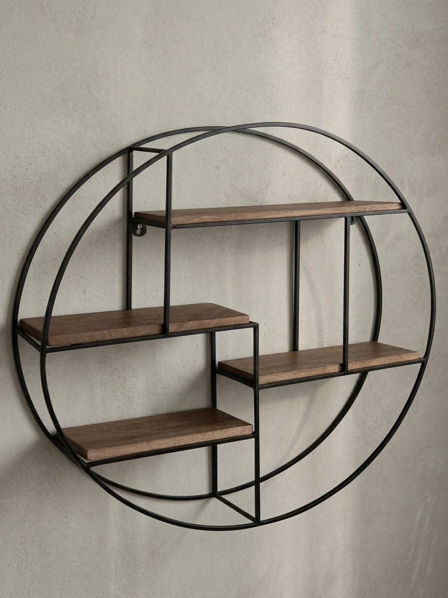 Frontansicht des runden Wandregals mit 70 cm Durchmesser, das die asymmetrische Anordnung der vier Ablagen aus Mangoholz im schwarzen Metallrahmen zeigt._