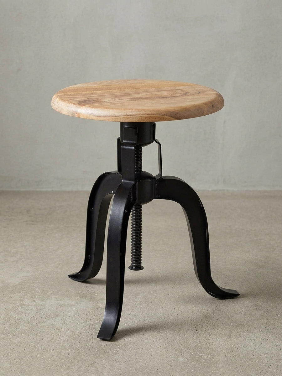 Freigestellter Drehhocker mit schwarzem Metallgestell und Sitzfläche aus Akazie Massivholz, Frontansicht. Der höhenverstellbare Industrie-Hocker ist ein Design-Highlight._