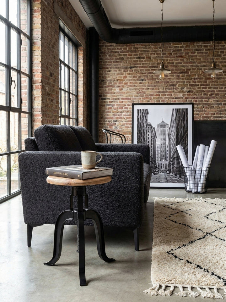 Industrie-Design Hocker von oben fotografiert, zeigt die runde Akazienholz-Sitzfläche und das schwarze Metallgestell auf einem hellen Teppich. Ideal als Deko- oder Sitzhocker._