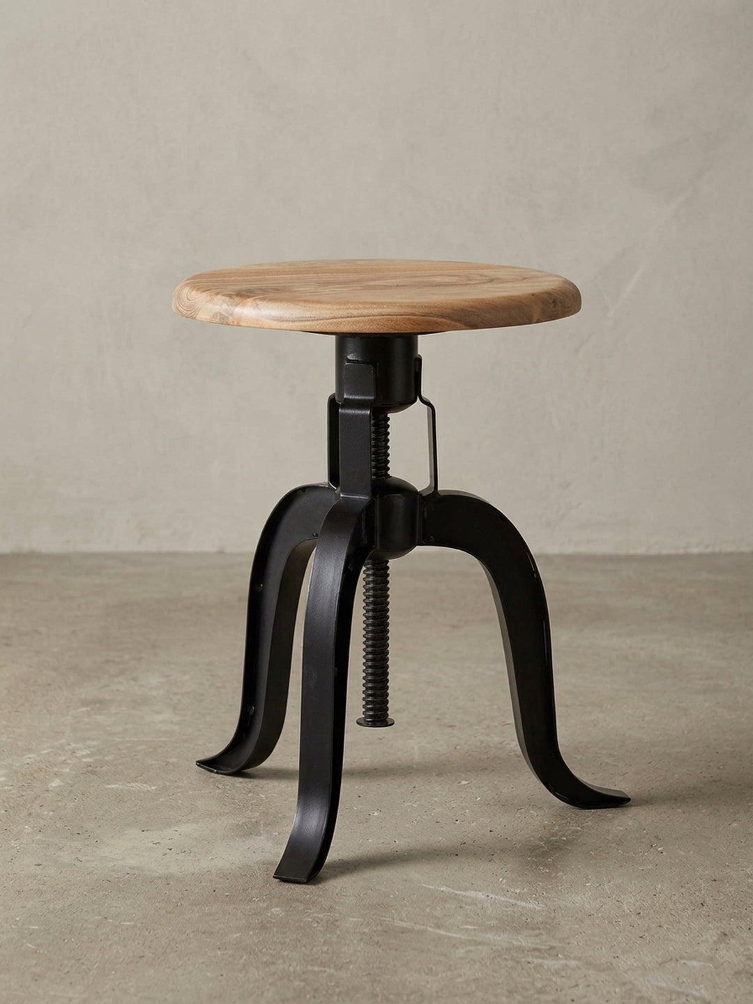 Design-Dekohocker als Gesamtbild. Der runde Hocker mit Akazienholz-Sitzfläche und schwarzem Metallgestell ist ein vielseitiges Möbelstück für Liebhaber des Industrie-Stils._