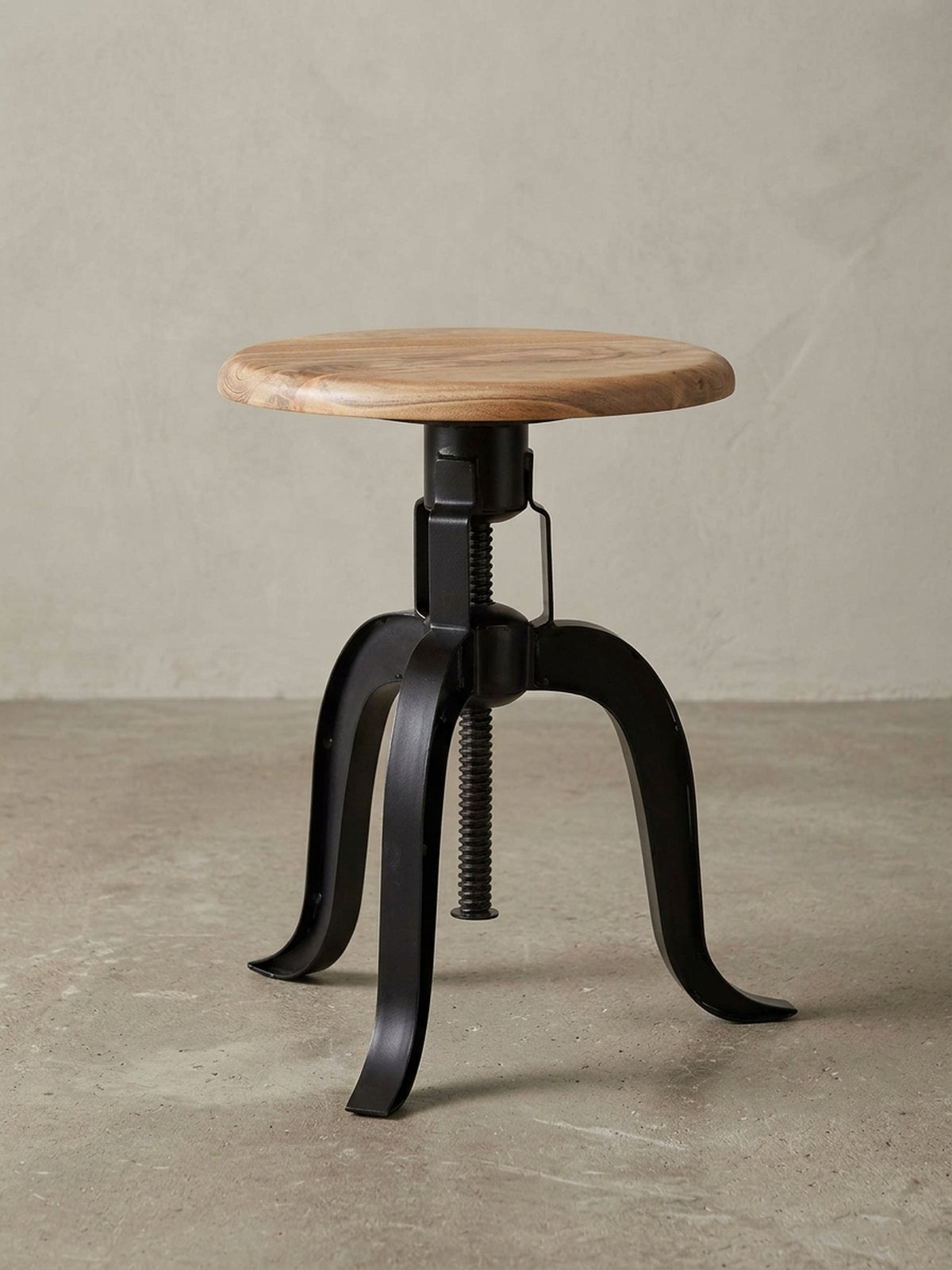 Design-Dekohocker als Gesamtbild. Der runde Hocker mit Akazienholz-Sitzfläche und schwarzem Metallgestell ist ein vielseitiges Möbelstück für Liebhaber des Industrie-Stils._