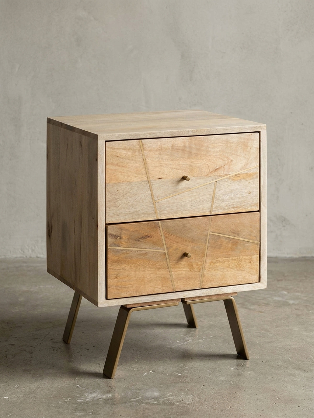Nachttisch aus massivem Mangoholz in Frontalansicht auf weißem Hintergrund. Der 56cm hohe Nachtschrank zeigt zwei geräumige Schubladen mit asymmetrischen Metall-Verzierungen._
