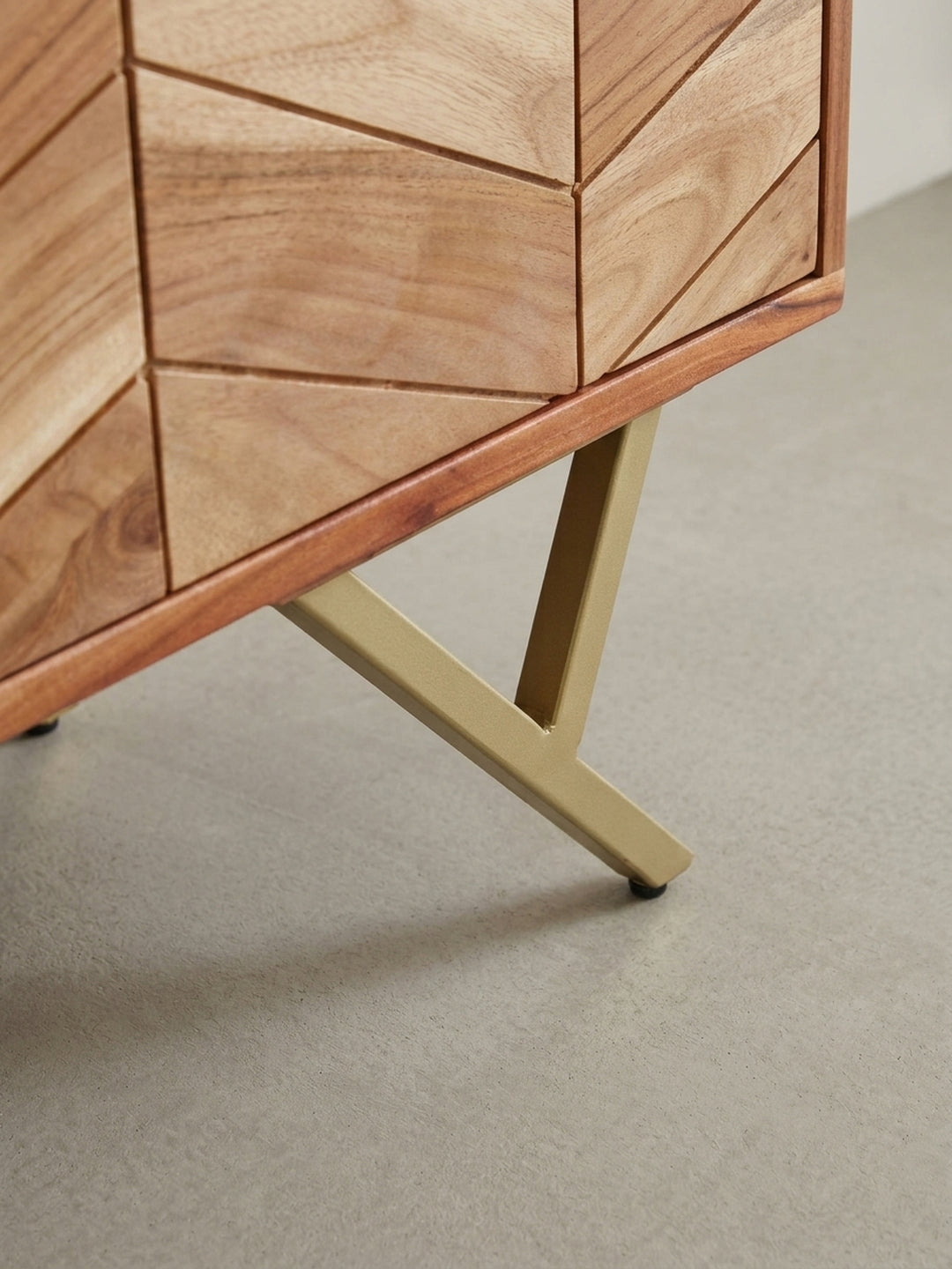 Nahaufnahme eines goldfarbenen, zylindrischen Griffs an der Schublade der Akazien-Kommode, der einen Hauch von Luxus und einen feinen Materialkontrast schafft._