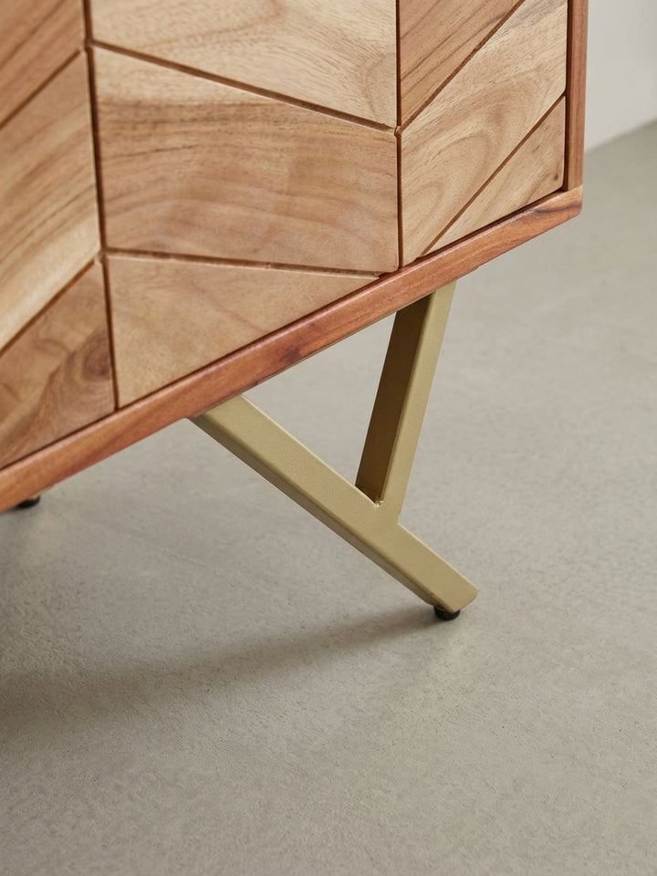 Nahaufnahme eines goldfarbenen, zylindrischen Griffs an der Schublade der Akazien-Kommode, der einen Hauch von Luxus und einen feinen Materialkontrast schafft._