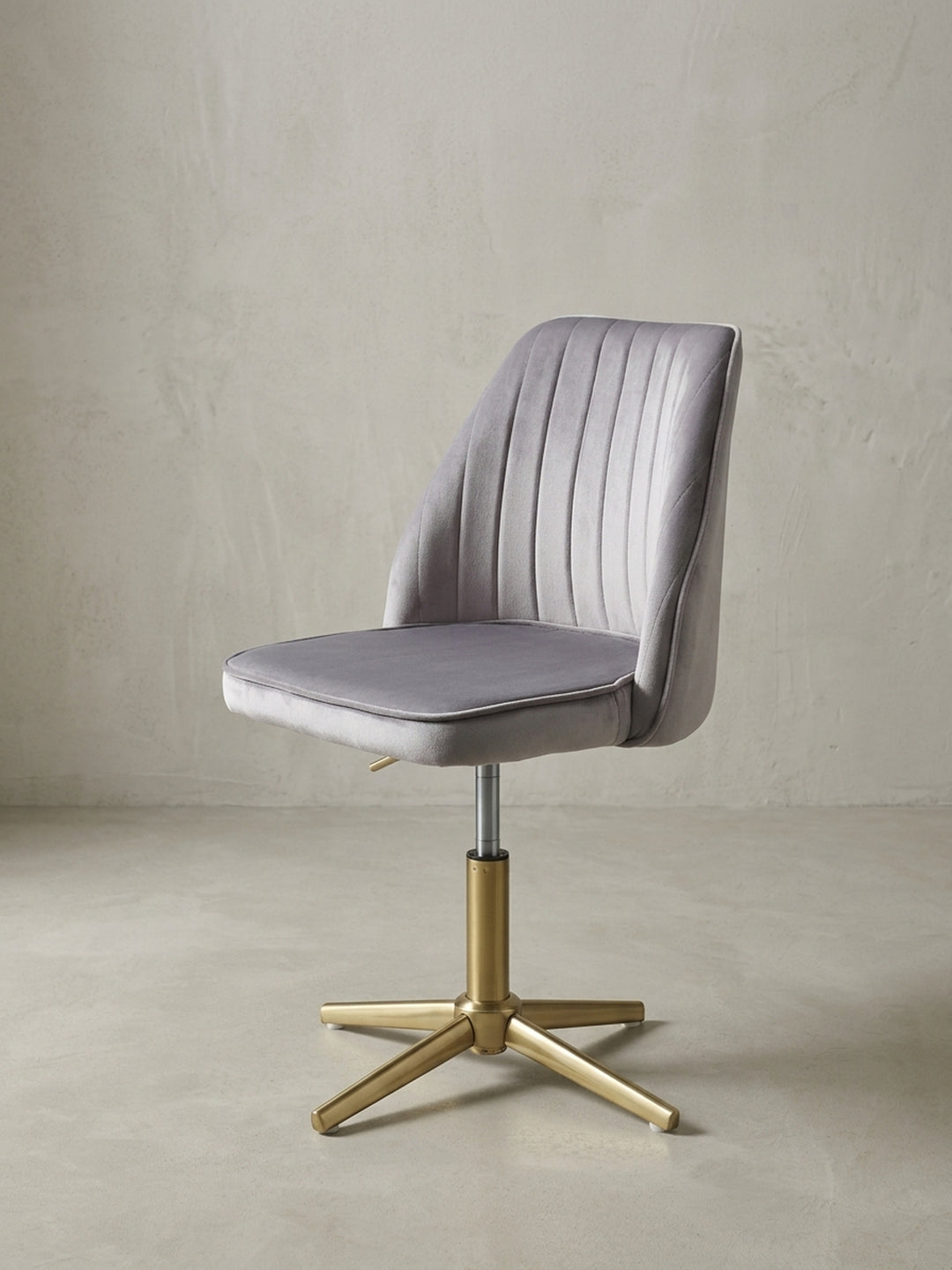 Moderner Schalenstuhl für das Home-Office in 3/4-Ansicht, der graue Samtbezug und das glänzende Goldgestell kommen elegant zur Geltung._