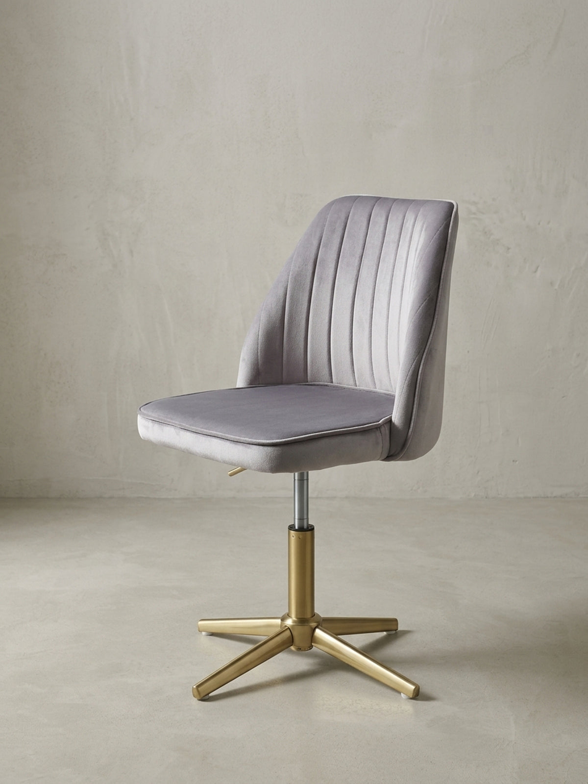 Moderner Schalenstuhl für das Home-Office in 3/4-Ansicht, der graue Samtbezug und das glänzende Goldgestell kommen elegant zur Geltung.