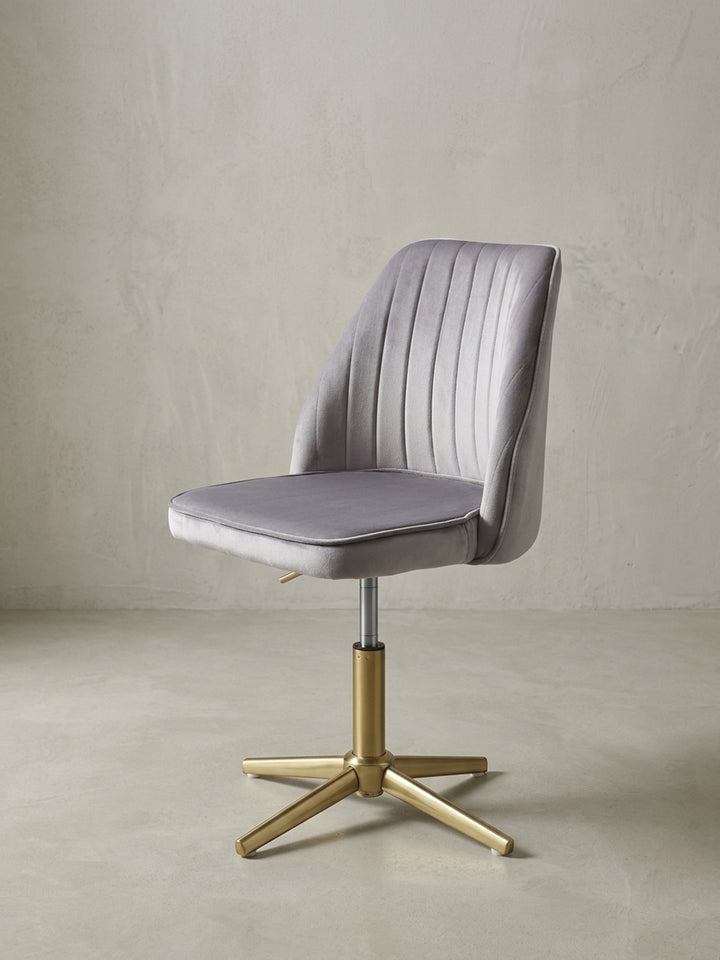 Moderner Schalenstuhl für das Home-Office in 3/4-Ansicht, der graue Samtbezug und das glänzende Goldgestell kommen elegant zur Geltung._