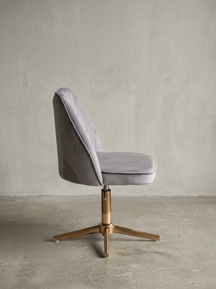 Der graue Samt-Schreibtischstuhl als Designobjekt, eine Gesamtübersicht hebt die Materialkombination und die moderne Formgebung hervor._