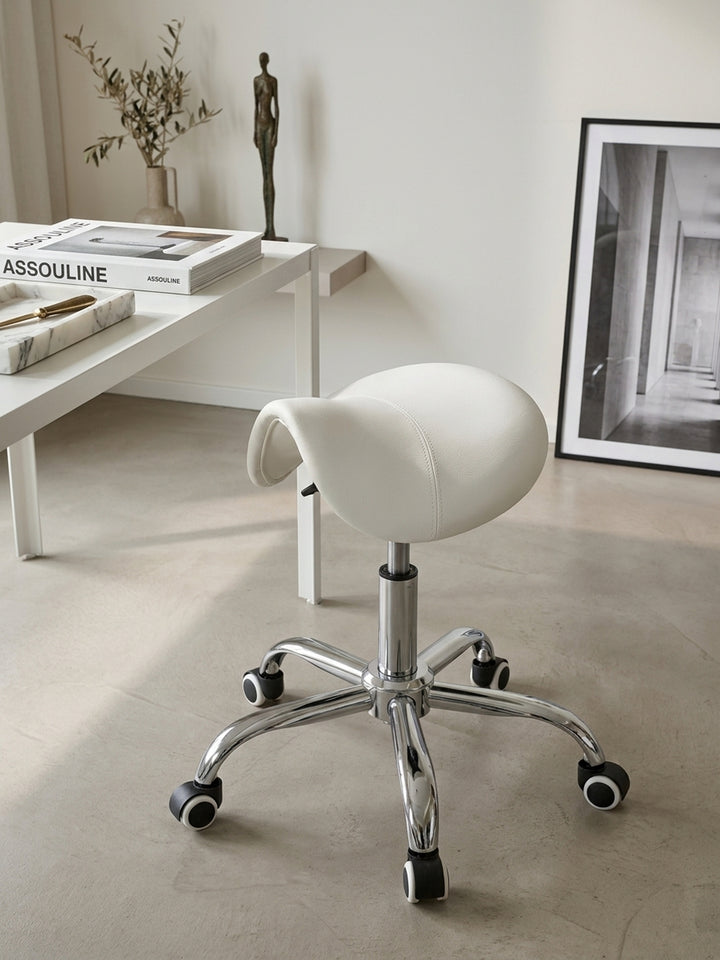 Nahaufnahme der weißen Kunstlederoberfläche des Praxishockers, bei der die feinen, präzisen Steppnähte der ergonomischen Sattelform im hellen Tageslicht gut sichtbar sind._