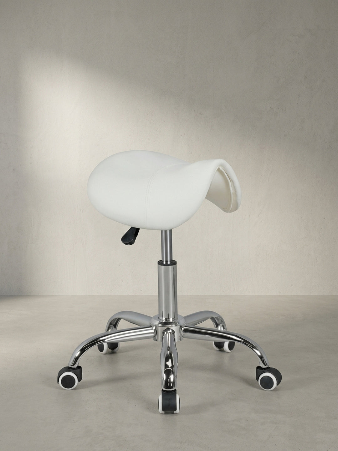 Frontale Ansicht des weißen Sattel-Hockers für das Heimbüro, der mit seinem glänzenden Chromfußkreuz und der ergonomischen Form eine professionelle, saubere Ästhetik ausstrahlt._
