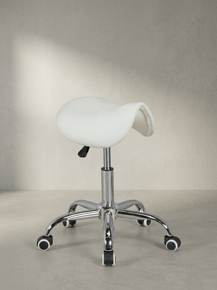 Frontale Ansicht des weißen Sattel-Hockers für das Heimbüro, der mit seinem glänzenden Chromfußkreuz und der ergonomischen Form eine professionelle, saubere Ästhetik ausstrahlt._