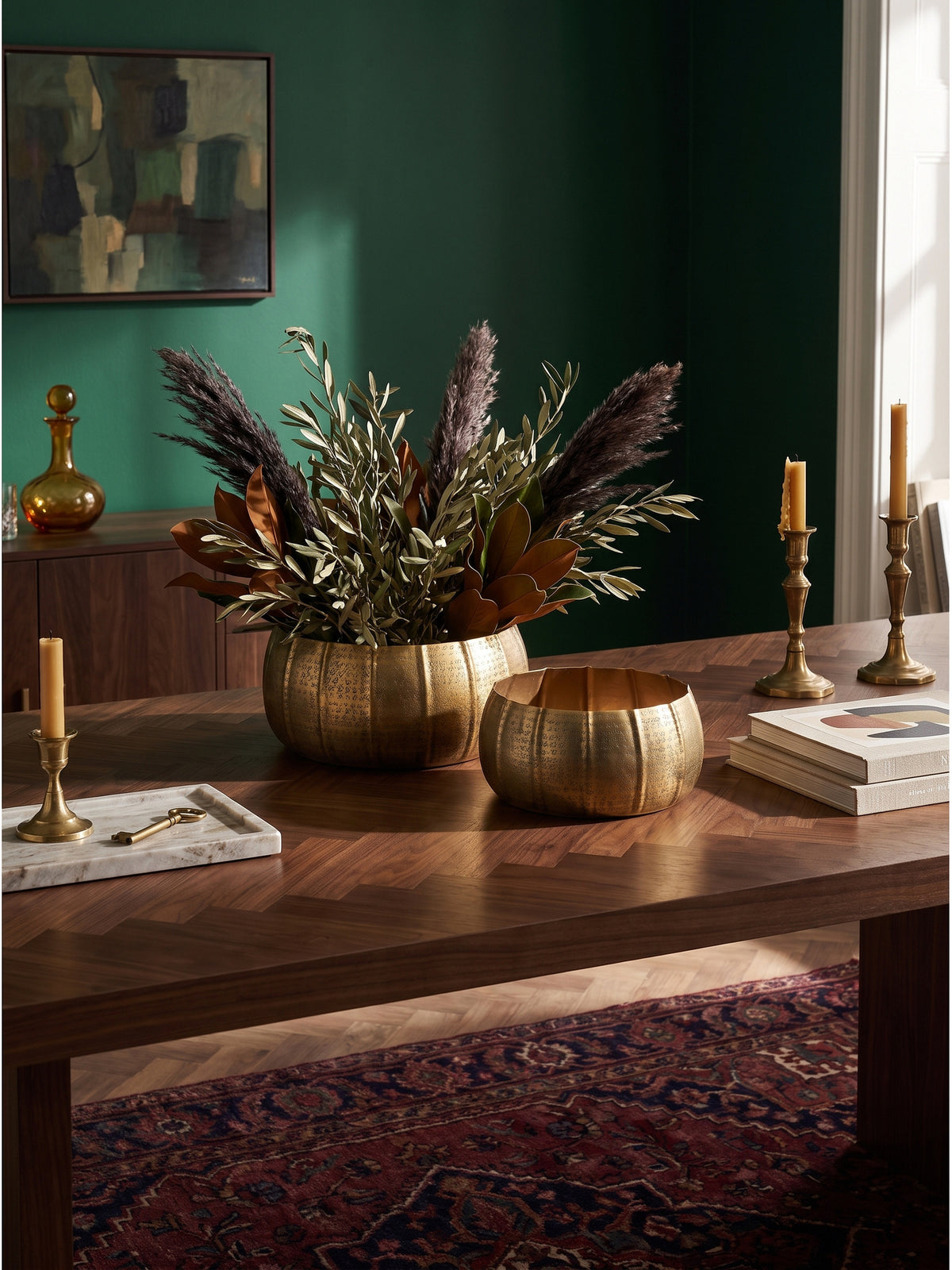 Großer goldfarbener Metall-Blumentopf neben einem antiken Lederbuch und einer Calacatta-Marmor-Schale auf einem eleganten Art-Deco-Sideboard