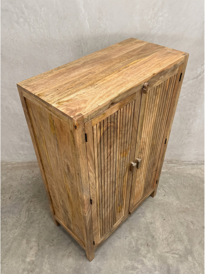 Leicht schräge Perspektive des 187 cm hohen Holzschranks, die die Tiefe der Türen und die massiven Holzfüße hervorhebt._